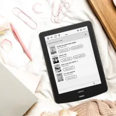 Czytnik ebooków z listą darmowych lektur i audiobooków, obok róż i filiżanka kawy.